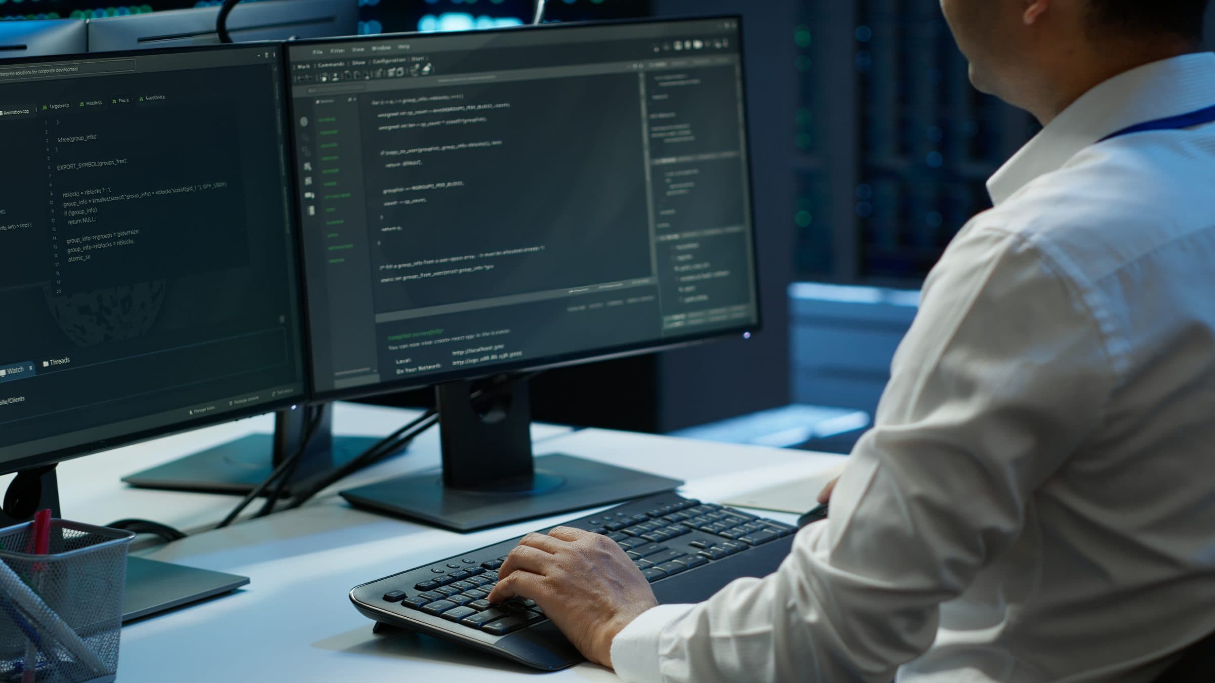 A developer working at two monitors