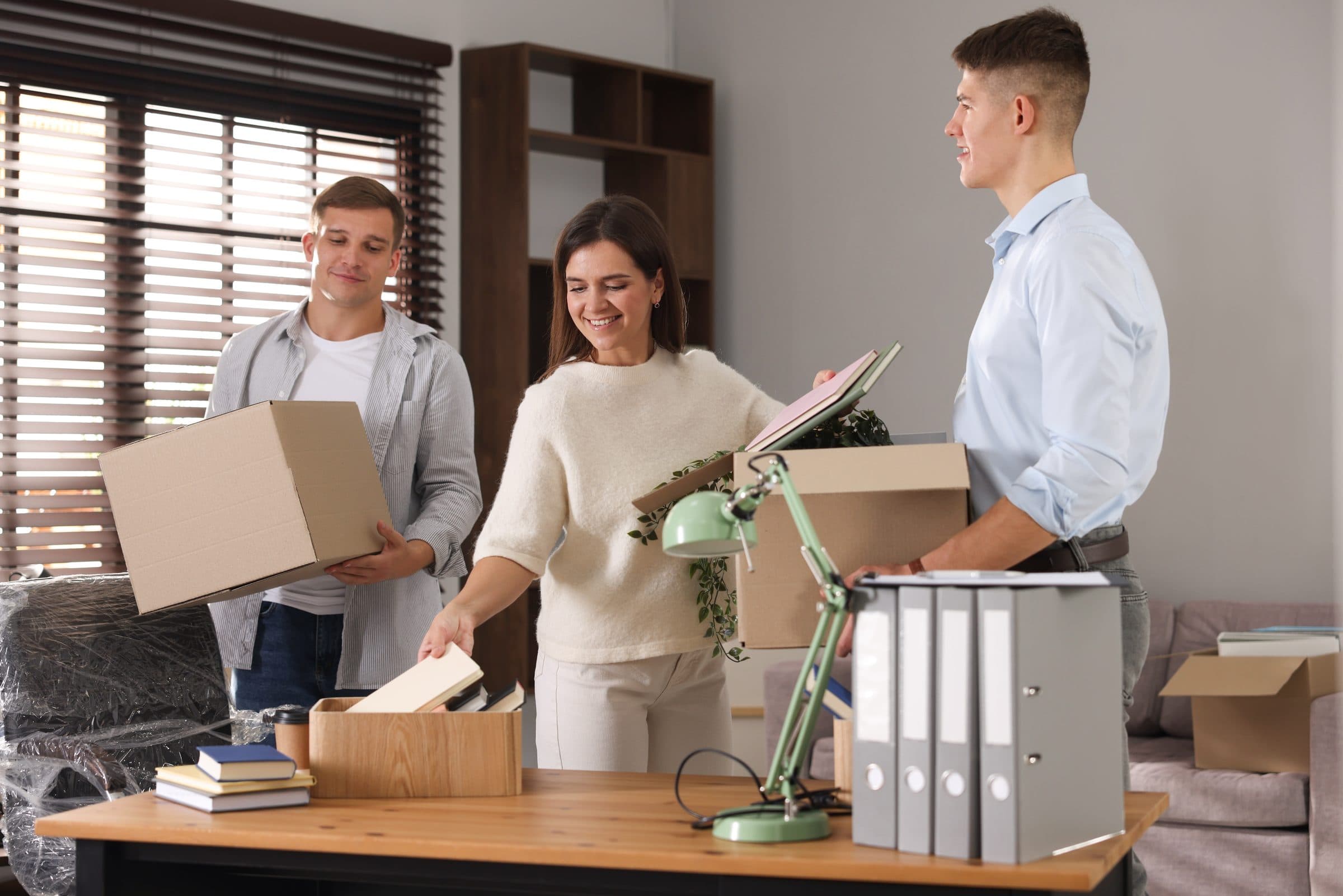 Three colleagues unpacking boxes in a new office